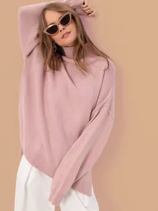 Close-up of a pink oversized turtleneck knit sweater worn by a model in soft lighting