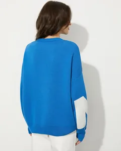 Rückansicht eines blauen Oversize-Strickpullovers mit weißem Buchstabendetail am Ärmel