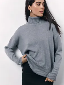 Close-up detail of a loose fit gray turtleneck knitted sweater worn by a female model