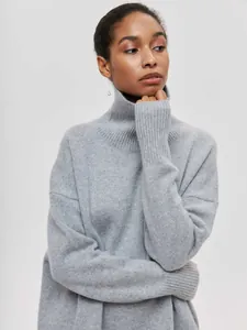 Détail d'un pull à col roulé gris ample avec des finitions en tricot côtelé doux