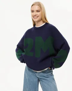 Detailansicht eines dunkelblauen Oversize-Strickpullovers mit grünem Buchstabenmuster.
