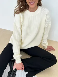 Close-up view of a woman wearing a cream-colored loose crew neck ribbed knit sweater