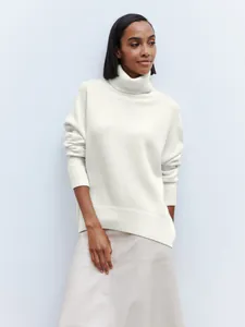 Detail view of a white oversized turtleneck sweater showing the relaxed fit and knit