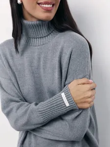 Detailed shot of a grey oversized turtleneck sweater with Italian yarn sleeve label