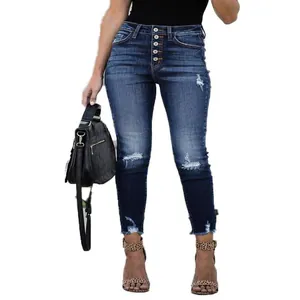 Close-up of high-waist button-fly skinny jeans with distressed ripped knees and frayed hem