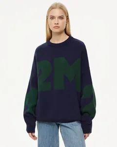 Detail eines übergroßen dunkelblauen Strickpullovers mit grünem Buchstabenmuster