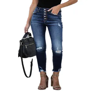 Detail view of high-waisted button fly skinny jeans with distressed knees and frayed hems.