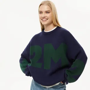 Oversized dunkelblauer Strickpullover mit großen grünen Buchstaben, getragen von Model