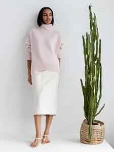 Femme portant un pull à col roulé en maille rose tendre avec une jupe midi blanche