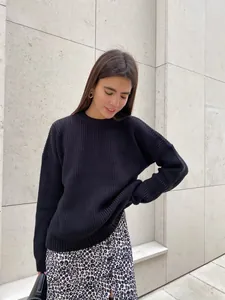 Close-up of women's loose crewneck black ribbed knit sweater on model outdoors