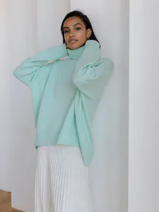 Oversized mint green turtleneck knit sweater for winter styled with white pleated pants