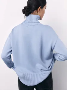 Back view of a loose light blue turtleneck sweater showing knitted texture and high collar