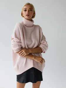 Macro detail view of an oversized light pink turtleneck knit sweater for women.