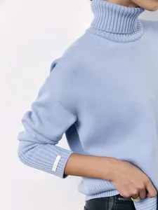 Detail of a light blue turtleneck sweater showing knit texture and ribbed cuff