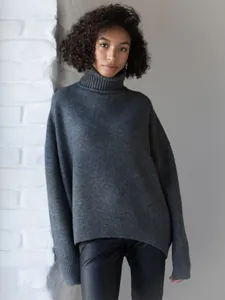 Close-up of a charcoal grey oversized turtleneck sweater featuring a chunky knit texture