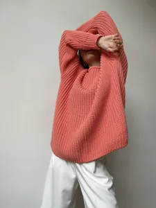 Detail view of chunky knit texture on oversized coral pink crewneck sweater for women.