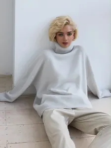 Detailed shot of an oversized light grey turtleneck knit sweater worn by a blonde model