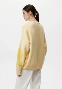 Rückansicht eines cremefarbenen Oversize-Strickpullovers mit gelbem Buchstabendruck