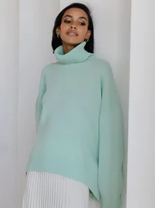 Detail of a soft mint green thick knit turtleneck sweater with a relaxed oversized fit