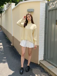 Élégant pull à col roulé jaune porté avec une jupe plissée blanche dans la rue.