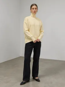 Femme portant un pull en maille à col roulé jaune pâle dans un style minimaliste élégant