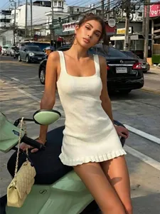 Elegante vestido de punto blanco con escote cuadrado y bajo con volantes en entorno urbano.