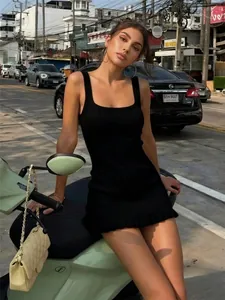 Primer plano de un mini vestido de punto negro con escote cuadrado y bajo con volantes