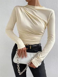 Vista detallada de los elegantes pliegues fruncidos en este top crema de manga larga