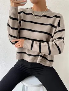 Detail view of a loose round neck striped knitted pullover sweater in beige and black.