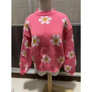 Vue détaillée d'un pull en maille rose ample avec de beaux motifs de marguerites.