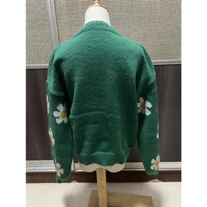 Vue arrière d'un pull en maille vert ample avec des motifs de marguerites aux manches.