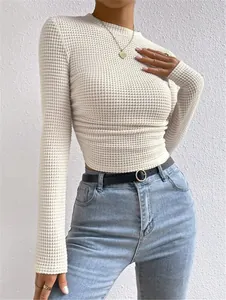 Nauwsluitend wit wafelgebreid dames-T-shirt met lange mouwen en rimpels gecombineerd met jeans