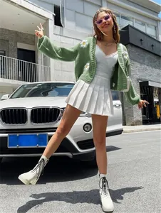 Street style λήψη μιας πράσινης πλεκτής ζακέτας με όμορφα σχέδια μαργαρίτας σε μοντέλο.