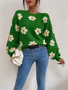 Vue détaillée d'un pull en maille verte avec de grands motifs floraux blancs