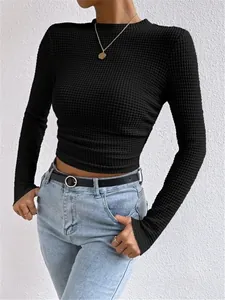 Detailopname van een zwarte crop top met wafelgebreide textuur, lange mouwen en een slanke pasvorm
