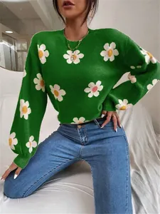 Vue détaillée d'un pull en tricot vert avec un motif de marguerites blanches et jaunes.