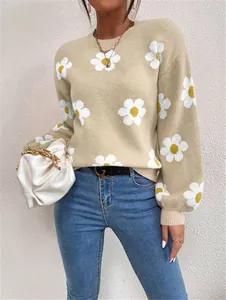 Détail d'un pull en maille lâche beige avec des motifs floraux blancs et col rond