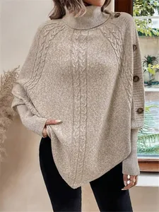 Dettaglio di un maglione beige a collo alto con maniche a pipistrello e bottoni decorativi