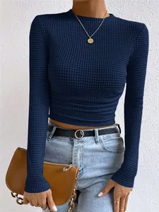 Detail van marineblauwe top met wafelstructuur, lange mouwen en een gerimpelde taille