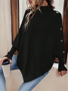 Dettaglio di un poncho nero a collo alto in maglia a trecce con bottoni laterali.