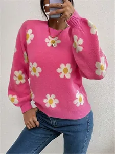 Détail de la texture en maille douce et du motif de marguerites jaunes sur ce pull rose