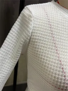 Close-up van witte wafeltextuur gebreide stof op een dames top met lange mouwen