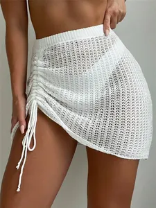 Detail of white hollow-out knit beach skirt featuring side drawstring ruched effect.