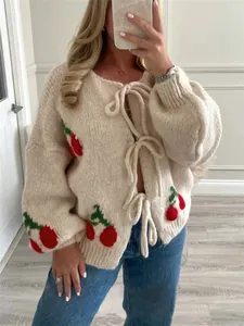 Dettaglio cardigan in maglia grossa crema con motivi a ciliegia e lacci frontali
