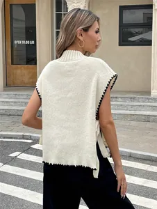 Rückendetail einer cremefarbenen Strickweste mit schwarzen Bogenkanten und Seitenschleifen.