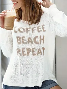 Close-up of white crew neck knit sweater with 'Coffee Beach Repeat' slogan design