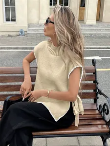 Nahaufnahme der beigen Strickweste mit weißem Kontrastrand und seitlicher Schleife.