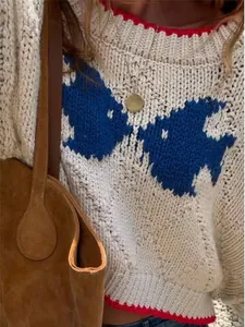 Close-up of vintage oversized knit sweater with bird pattern and red trim detail