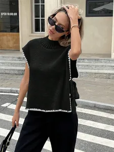 Eleganter schwarzer ärmelloser Strickpullunder mit weißem Wellensaum und Seitenschleife.