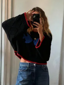 Close-up of retro black knit sweater with red trim and blue fish jacquard pattern.